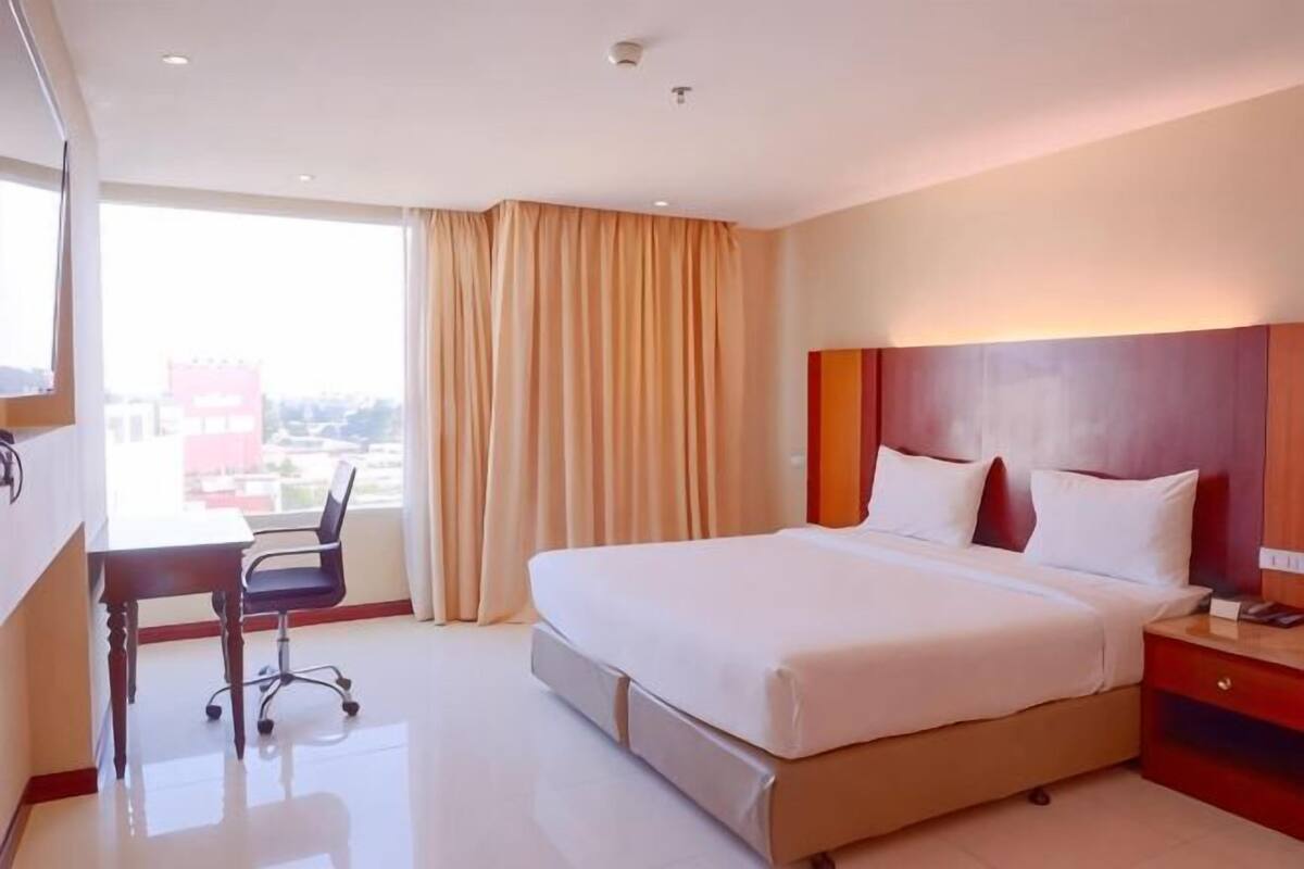 A hotel room with a large bed, a desk, and a view of the city.