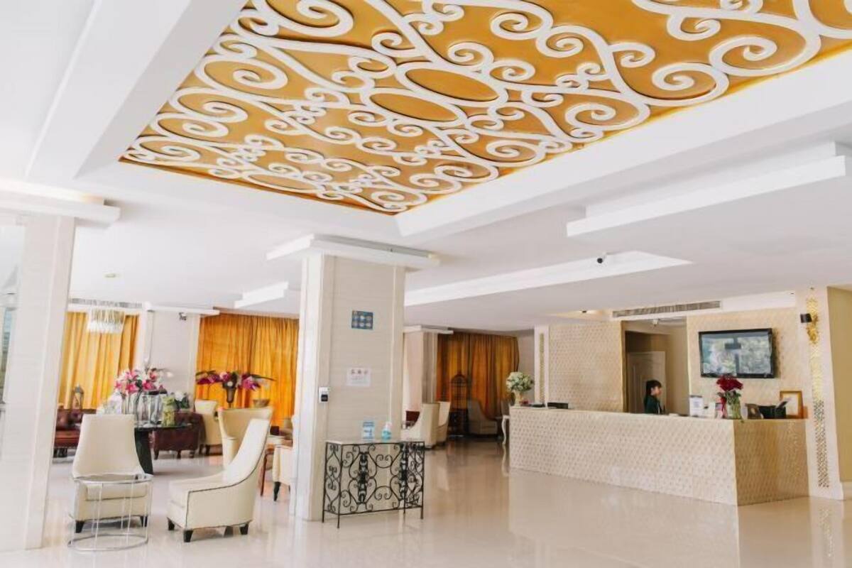 A hotel lobby with a reception desk, seating area, and decorative ceiling.