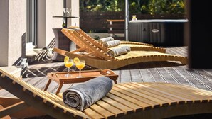 A sunlit outdoor lounge area with wooden loungers, a small table with glasses of orange juice, and a barbecue grill in the background. - 3 bedroom nice home in Srinjine (Srinjine)