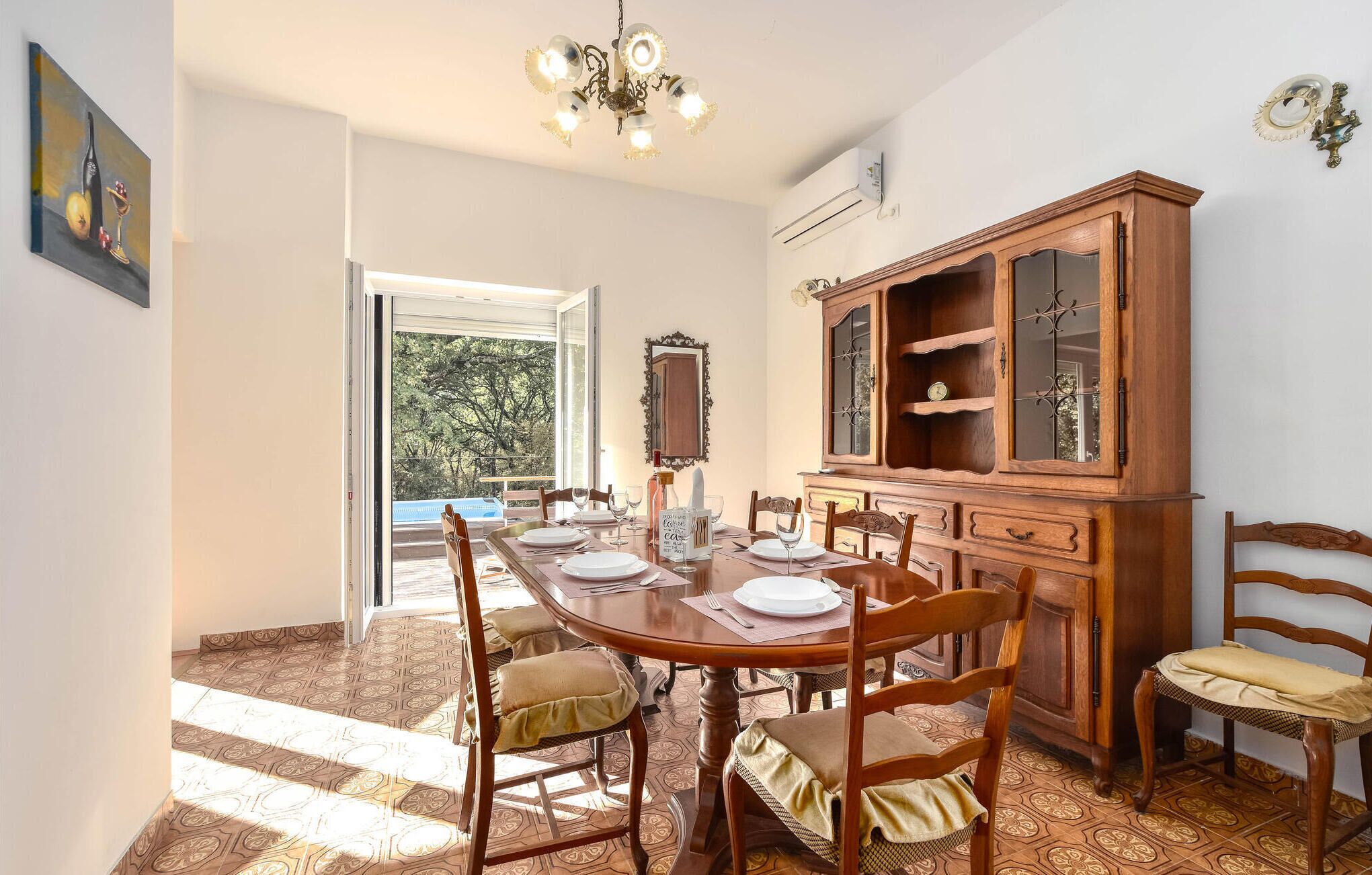 Een eetruimte met een houten tafel voor zes personen, omringd door stoelen. Een houten kast met glazen deuren bevindt zich rechts.