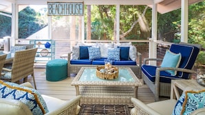 A covered outdoor seating area with wicker furniture, a glass coffee table, and a sign reading 'BEACHHOUSE'. - Family-Friendly; Steps to Beach; Fabulous Backyard w/ Screened Porch, Expansive Back Deck & Fire Pit (Isle of Palms)