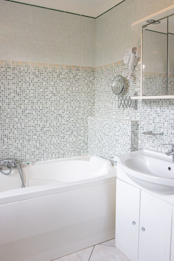 A bathroom with a white bathtub, a sink, and a mirror. - MIL ROSES EN BAIE 9 PEOPLE NEAR MARQUENTERRE (SAINT QUENTIN EN TOURMONT)