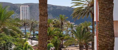 A resort with palm trees, a pool, and a mountain backdrop.