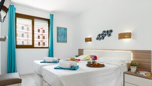 A hotel room with two beds, a small desk, and a window with curtains. - 211 Los Cristianos First Sea Line, Swimming pool (Los Cristianos)