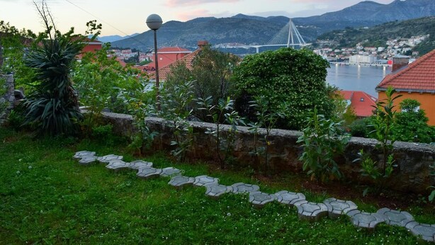 A coastal town with a prominent bridge, lush greenery, and a stone wall with a patterned walkway. - Leela Apartment,  ideal for romantic gateway! (Dubrovnik)