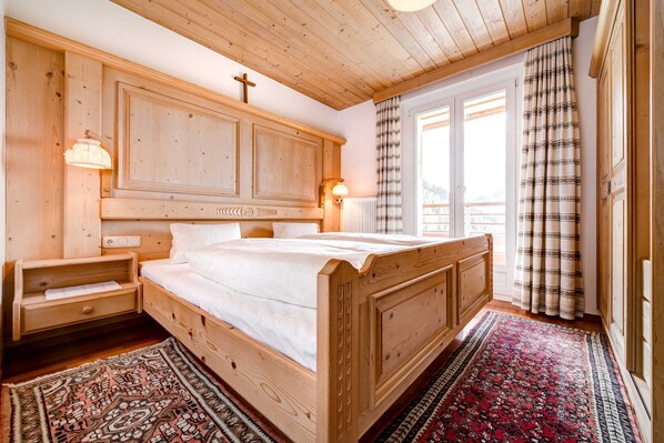 A wooden bedroom with a bed, nightstands, and a window with curtains.