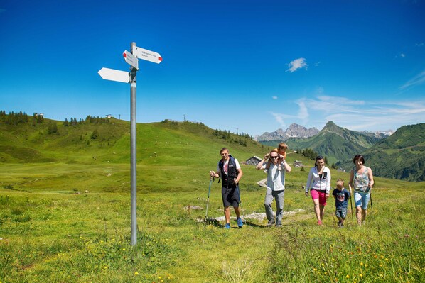 A family hiking in a grassy field with a signpost in the foreground.