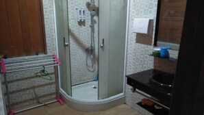 A bathroom with a glass-enclosed shower, a wooden door, a towel rack, and a mirror above a black countertop. - Comfortable, Great and Cheap (Palu)