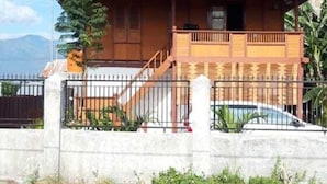 A two-story house with a red-tiled roof, a balcony, and a gated entrance. - Comfortable, Great and Cheap (Palu)