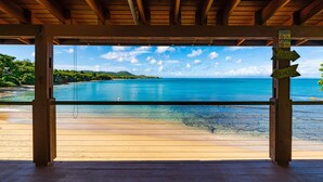 Eine Holzhütte mit Blick auf einen Strand und ein klares, blaues Meer.