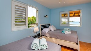 Ein Zimmer mit zwei Betten, einem Deckenventilator und Meerblick.