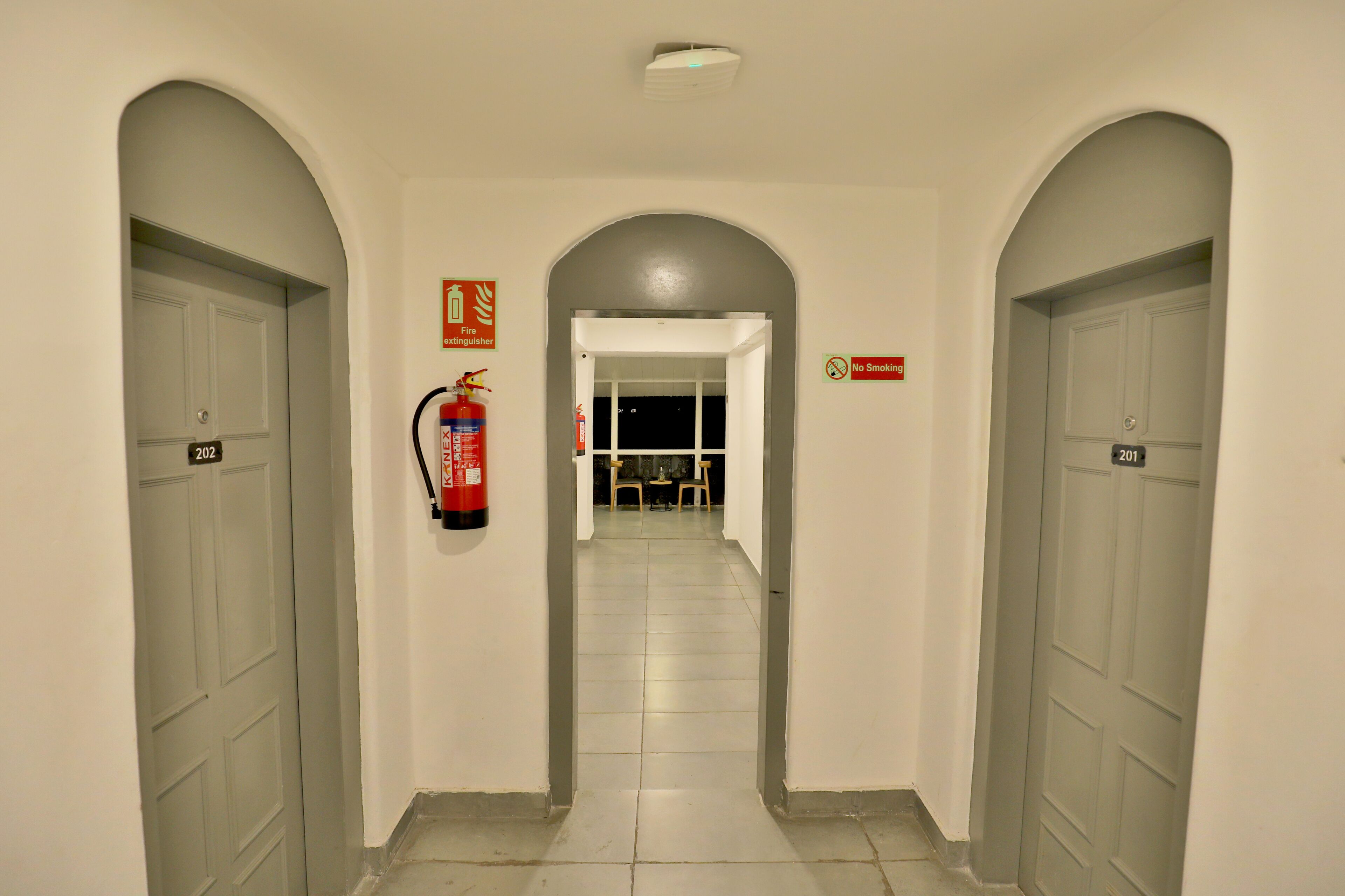 A hallway with arched doorways, a fire extinguisher, and a 'No Smoking' sign.