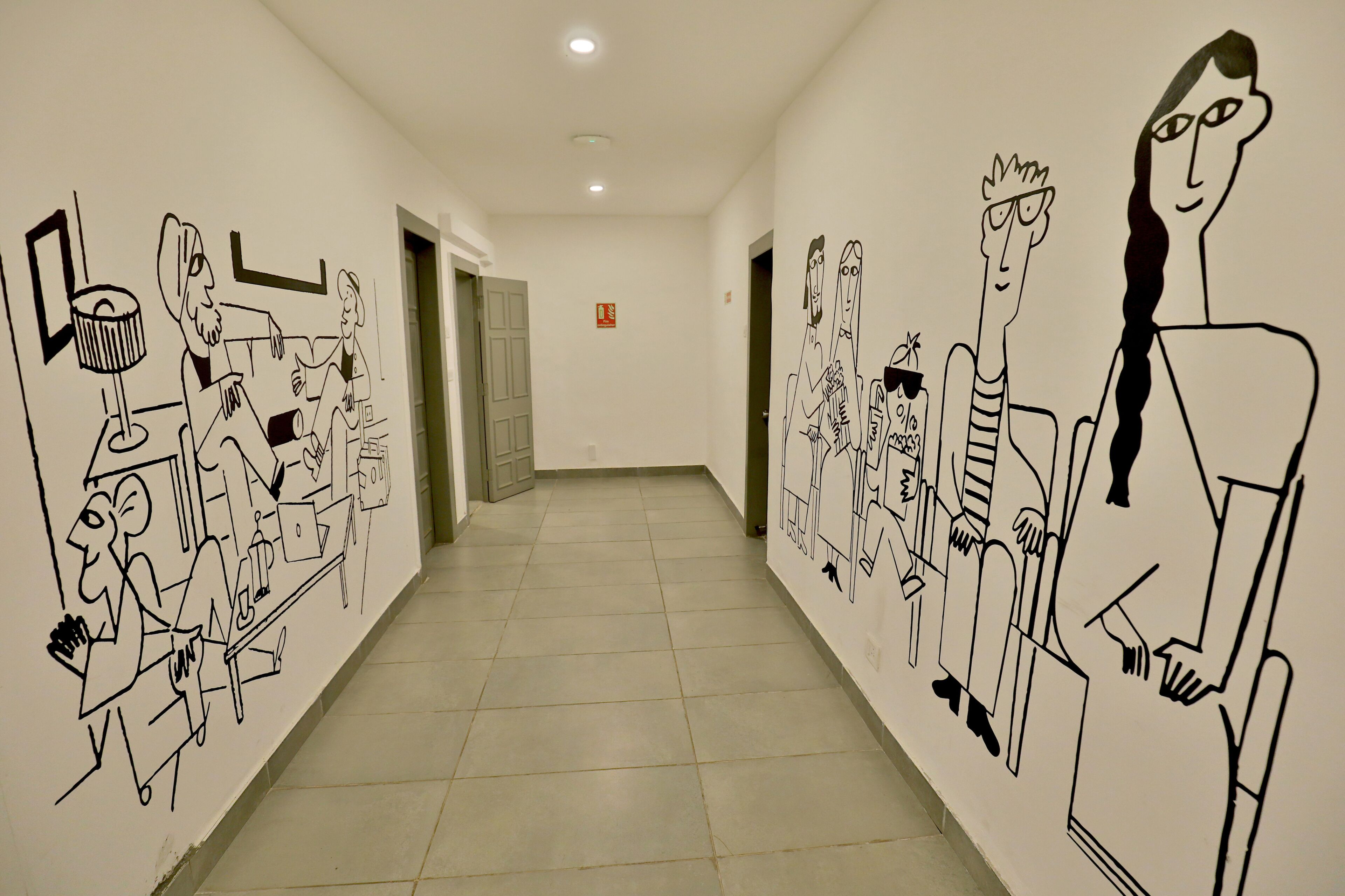 Un pasillo decorado con dibujos lineales en blanco y negro de personas en diferentes poses.