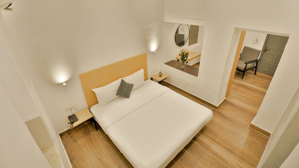 A modern hotel room with a large bed, bedside tables, a mirror, and a desk. - Ritz Heritage (Mawal)