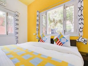 Una habitación con una cama, dos ventanas con cortinas y vistas al exterior.