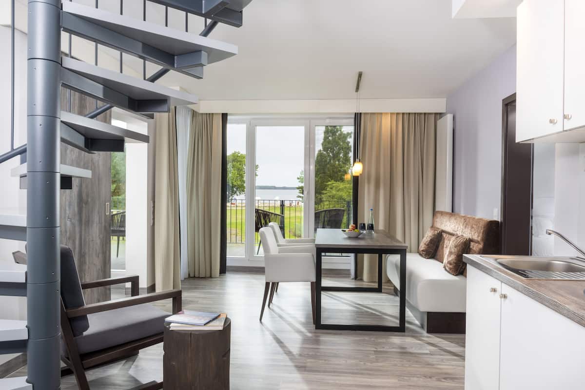 A modern living room with a staircase, a dining area, and a kitchen.