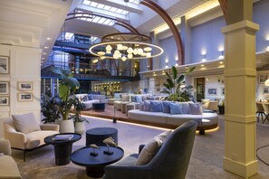 A spacious lobby with a high ceiling, modern lighting, and comfortable seating areas. - Aedenlife Hotel & Resort Rügen (Trent)
