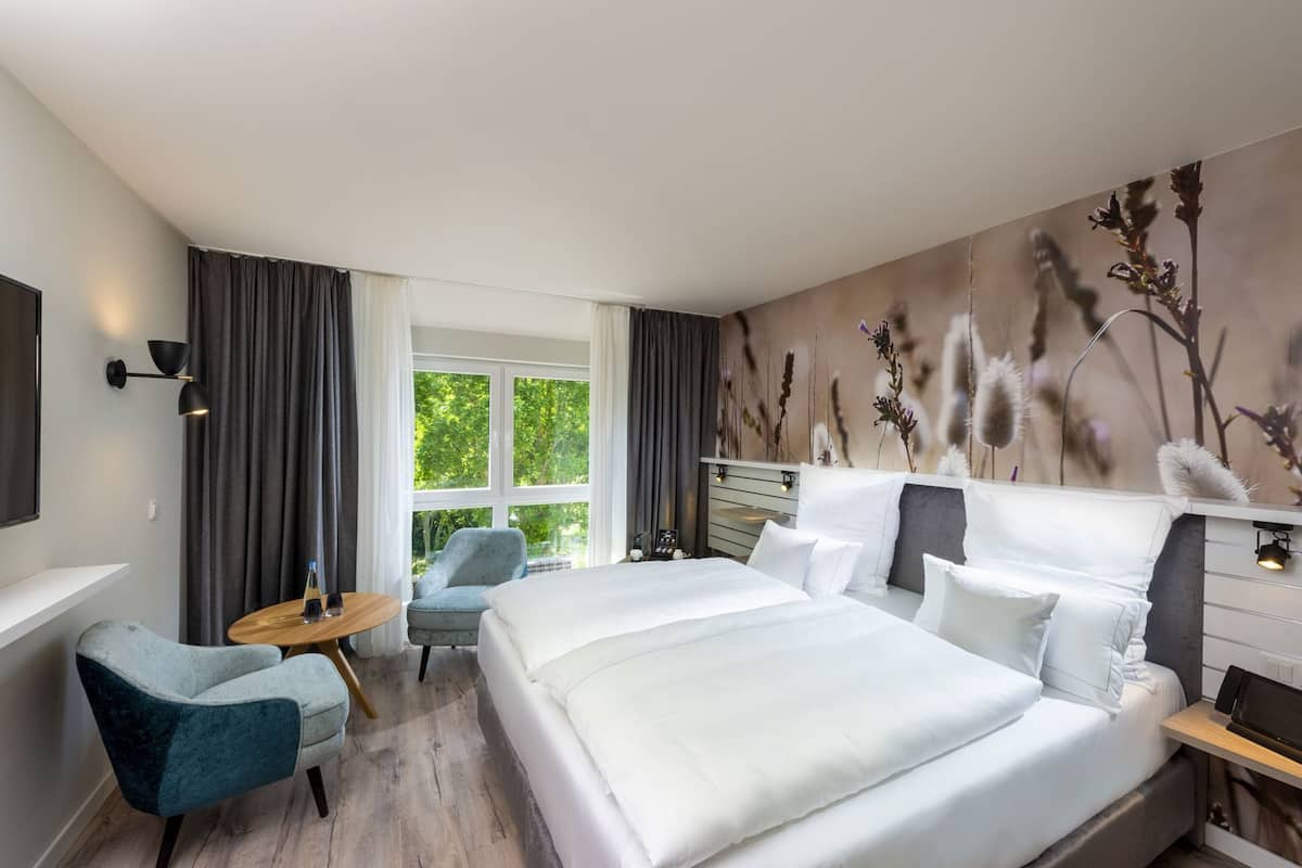 A hotel room with a large bed, a desk, a chair, and a TV.
