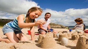 Une scène de plage où des gens construisent des châteaux de sable.