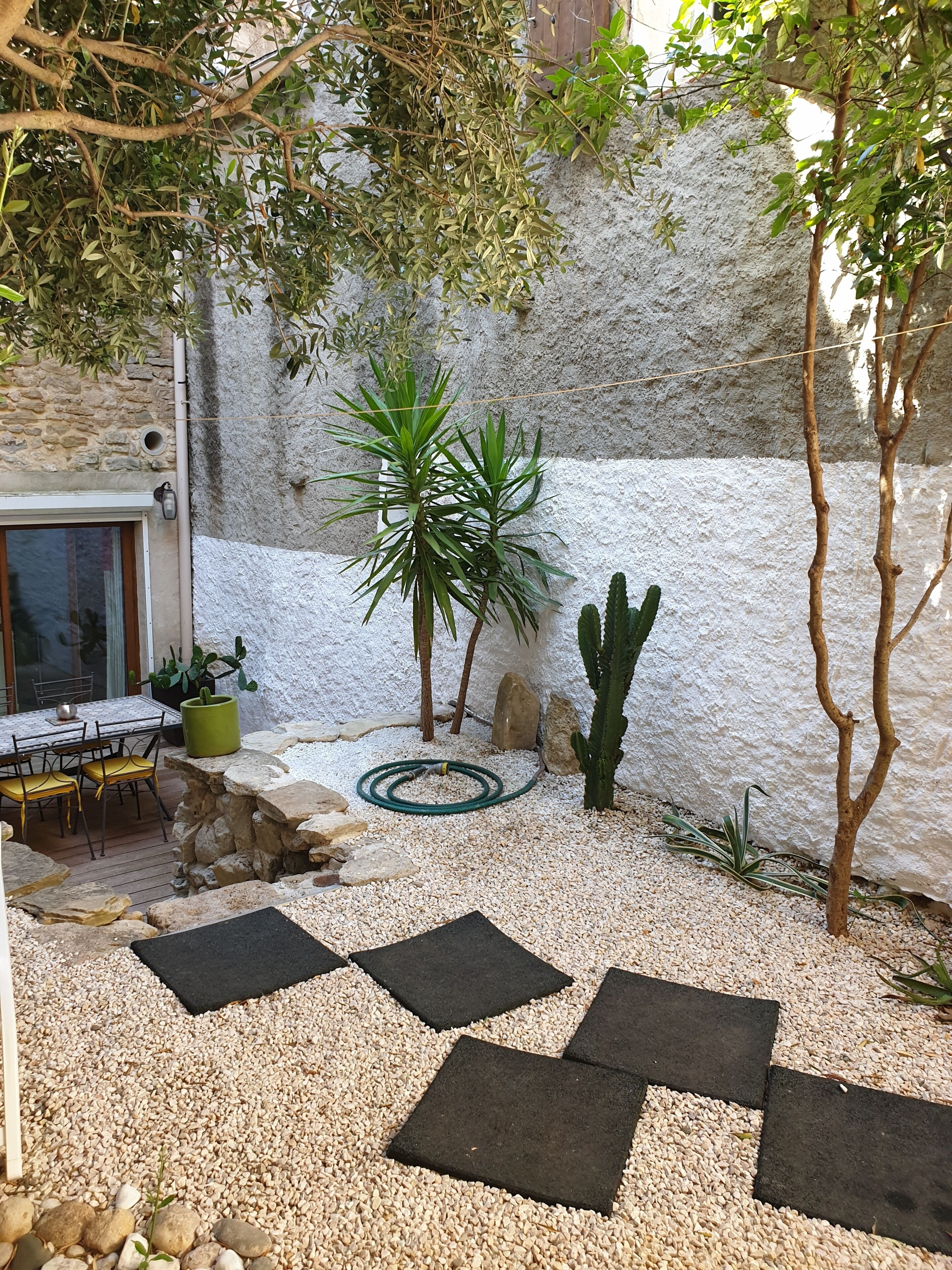 A patio with a table and chairs, surrounded by rocks and plants.