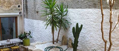 A patio with a table and chairs, surrounded by rocks and plants.