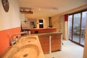 A kitchen with a double sink, wooden cabinets, a built-in stove, and a sliding glass door to a patio.