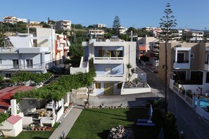 A modern building with a flat roof, a small garden, and a pool. - Danaos Beach Apartments (Rethymno)