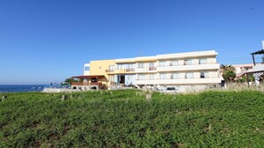 A multi-story hotel with balconies, a pool area, and a view of the sea. - Danaos Beach Apartments (Rethymno)