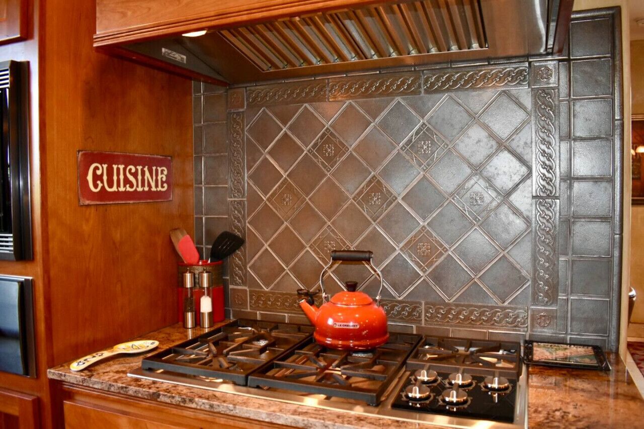 Una cocina con estufa a gas, un hervidor rojo y un letrero que dice 'CUISINE'.