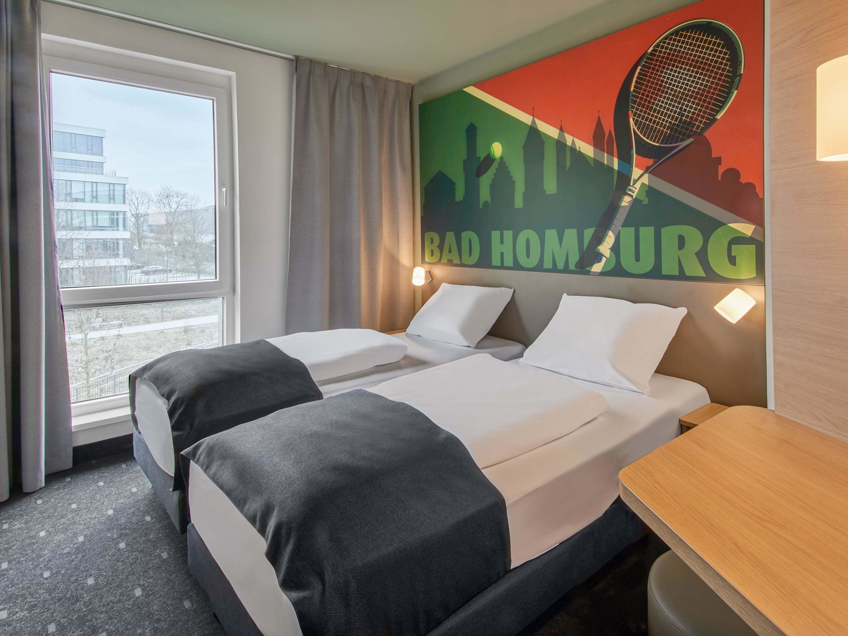 Habitación de hotel con dos camas, vista a la ciudad y una raqueta de tenis en la pared.