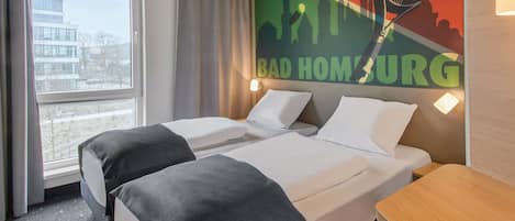 Habitación de hotel con dos camas, vista a la ciudad y una raqueta de tenis en la pared.