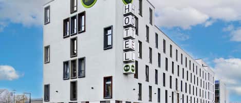 Un moderno edificio de B&B con fachada blanca, varias ventanas y logotipos de B&B.