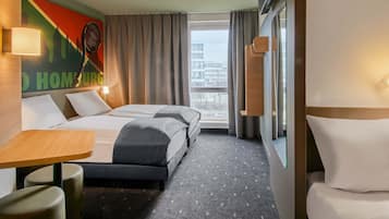 Ein Hotelzimmer mit zwei Betten, einem Schreibtisch, einem Stuhl und einem großen Fenster mit Blick auf die Stadt.