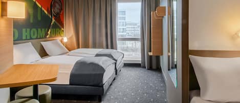A hotel room with two beds, a desk, a chair, and a large window offering a city view.