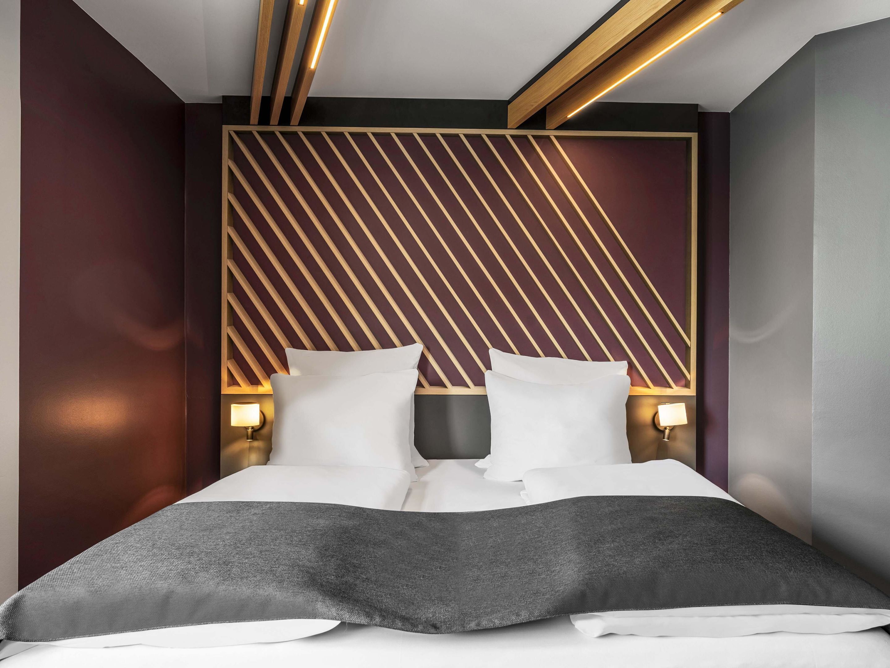 A modern bedroom with a bed, two bedside tables, and a geometric-patterned headboard.