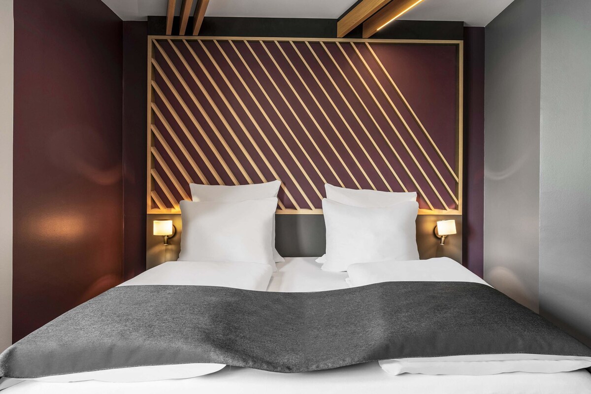 A modern bedroom with a bed, two bedside tables, and a geometric-patterned headboard.