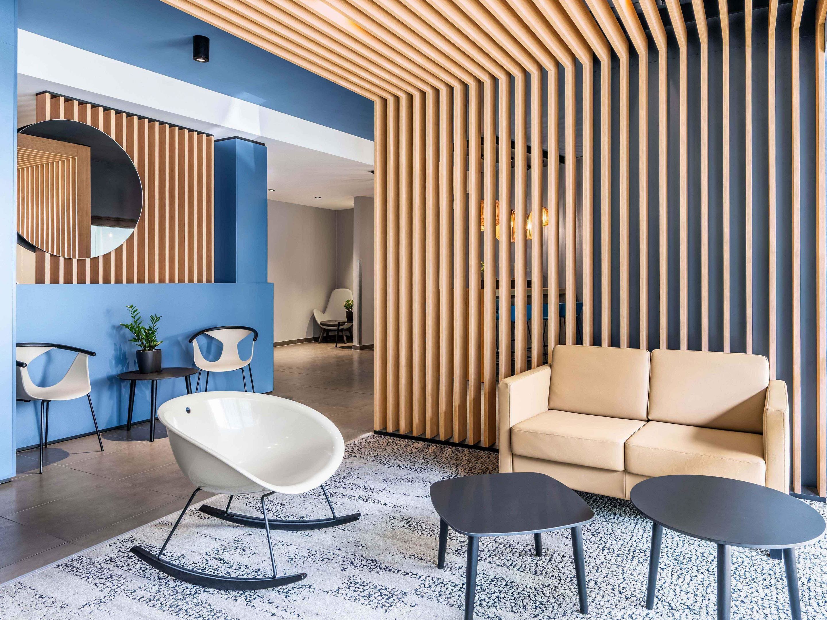 Ein moderner Lounge-Bereich mit einer Couch, zwei Schaukelstühlen und einem kleinen Tisch.