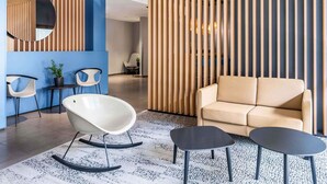 Un espace de détente moderne comprenant un canapé, deux fauteuils à bascule et une petite table.