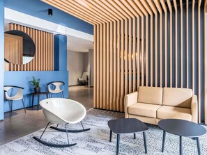 A modern lounge area with a sofa, two rocking chairs, and a small table. - B&B Hotel Schweinfurt-City (Schweinfurt)