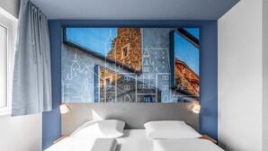A hotel room with a bed, a window with curtains, and a wall with a cityscape artwork. - B&B Hotel Schweinfurt-City (Schweinfurt)