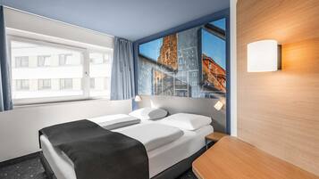 Ein Hotelzimmer mit Bett, Nachttisch, einem Fenster mit Vorhängen und einer Wandleuchte.