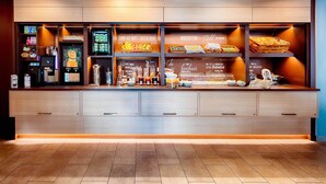 A breakfast bar with a variety of food items and beverages, including a coffee machine and a fruit display. - B&B Hotel Schweinfurt-City (Schweinfurt)