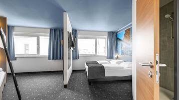 Une chambre d’hôtel comprenant un lit, un bureau, une chaise, une fenêtre avec des rideaux et un espace douche.
