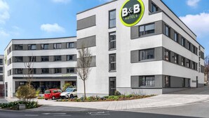 A modern B&B hotel with a reception area, parking, and a clear sky. - B&B Hotel Schweinfurt-City (Schweinfurt)