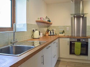 A kitchen with a stainless steel sink, a toaster, a kettle, and a built-in oven.