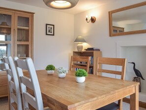 A dining area with a wooden table, white chairs, and potted plants. - 3 bedroom accommodation in Mathry (Mathry)