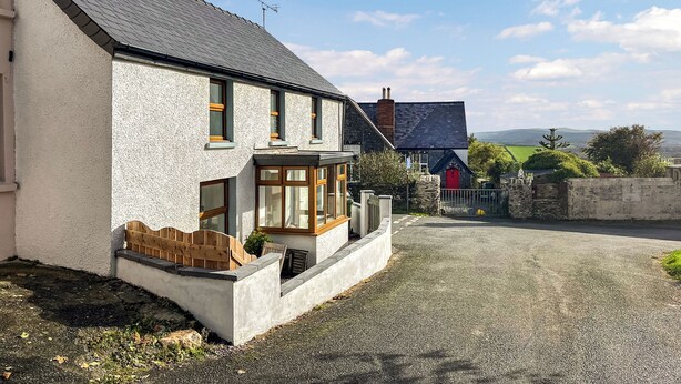 Une maison à deux étages avec une allée en gravier et une porte rouge.