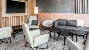 Ett modernt loungeområde med en platt-TV, bekväma sittplatser och en mönstrad matta.