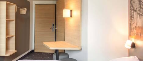 Una habitación de hotel con una cama, un escritorio, una silla y un armario.