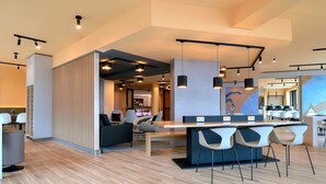 Een moderne hotellobby met een bar, zitplaatsen en een uitzicht op de eetruimte.